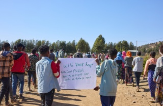 Children holding up a sign asking for help.