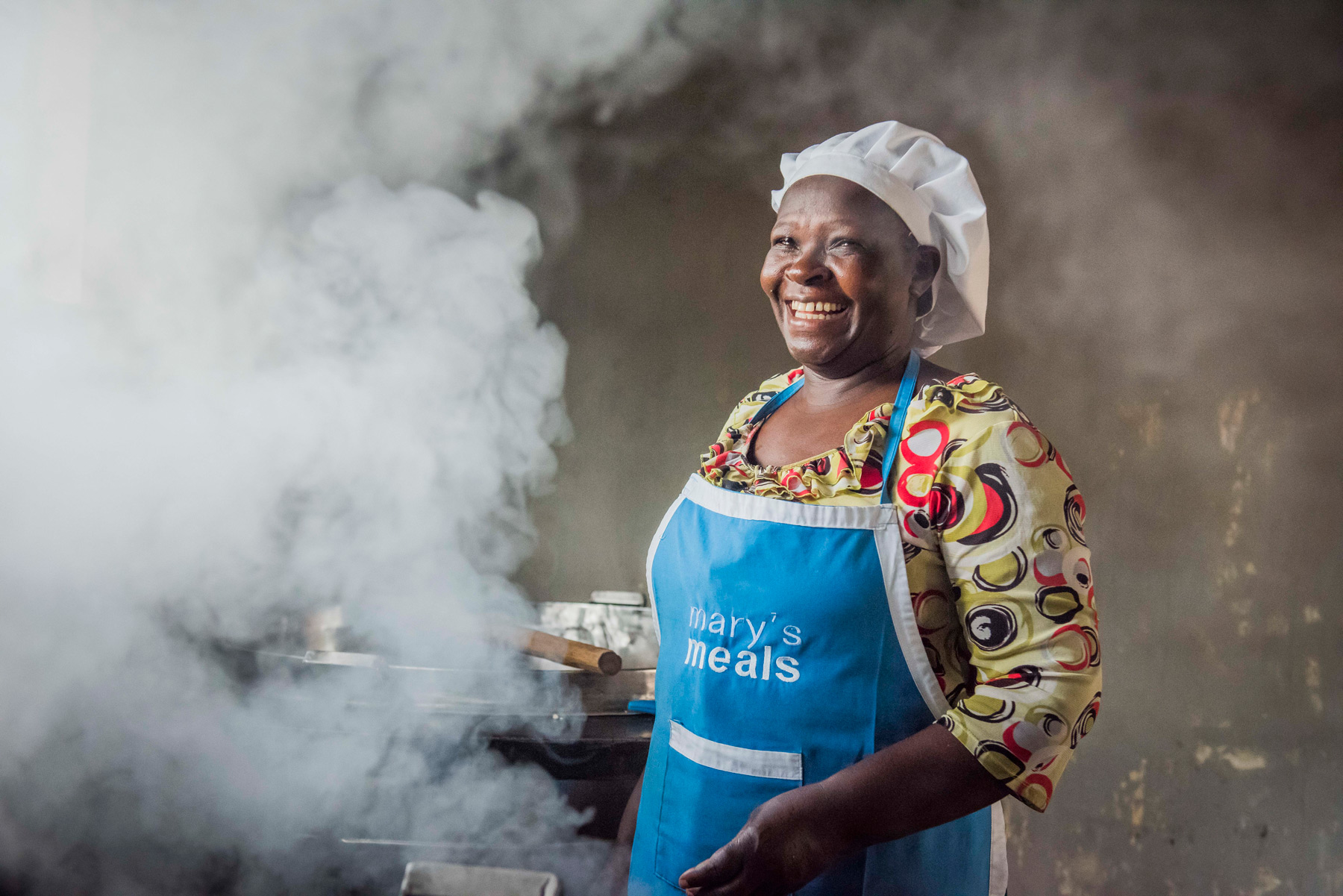 A volunteer cook laughs as she prepares food