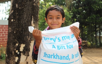 A boy in India holds a delivery of food from Mary's Meals