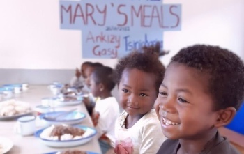 children smiling happily in front of bowls full of food
