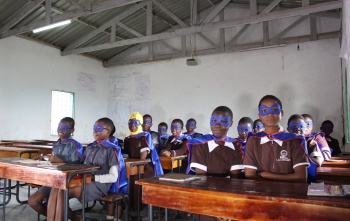 classroom full of children dressed as superheroes with capes and masks