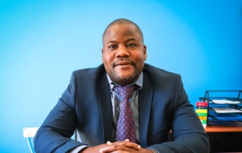 mid shot of a man wearing a suit against a blue blackground