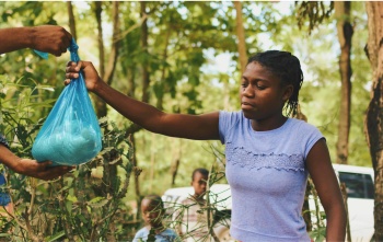 One volunteer passes a package of food to another.