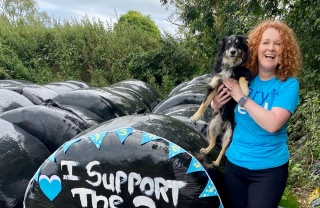 a woman holding a dog in front of a sign that reads 'I support the 2 million children'