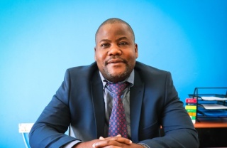 mid shot of a man wearing a suit against a blue blackground