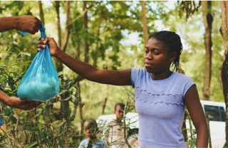 One volunteer passes a package of food to another.