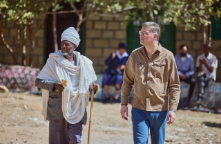 Image of Mary's Meals founder Magnus MacFarlane-Barrow walking with a village elder in Tigray.