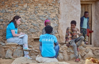 Mary's Meals members of staff in discussion with Letemariam and her grandson.