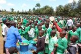 a large group of children gathering receiving school meals