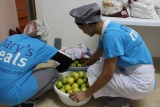 two people kneeling in front of a bowl of fruit