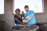 two people stirring a vat of porridge together