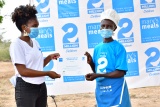 woman receiving a certificate from another woman in front of a branded background