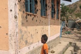 boy standing next to building with bullet holes in Ethiopia