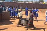 Image of volunteer cooks carrying a pot of cooked food.