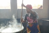 Image of a volunteer cook stirring a pot of food being prepared for the children.