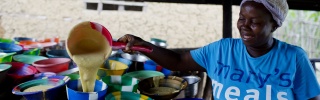 Mary's Meals volunteer pouring porridge into smaller bowls