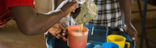 A volunteer from Zambia serving Mary's Meals to children at school. 