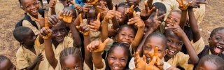 A group of children smiling and waving as they attend school in Liberia.