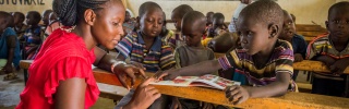 A teacher attends to pupils in Kenya