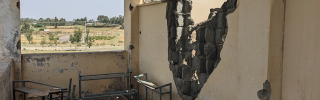 Image looking out of a building which has been left in ruin after the recent conflict.