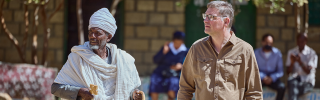 Image of Mary's Meals founder Magnus MacFarlane-Barrow walking with a village elder in Tigray.