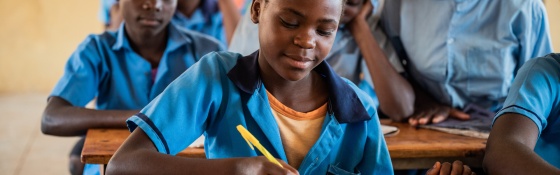 A child from Zambia writing in her jotter while learning in class.