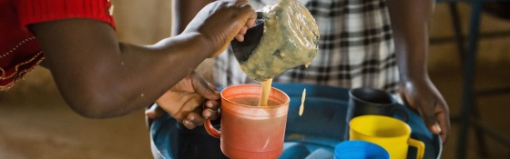 A volunteer from Zambia serving Mary's Meals to children at school. 
