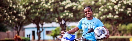 A volunteer in Zambia rests against her motorbike