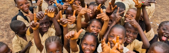 A group of children smiling and waving as they attend school in Liberia.