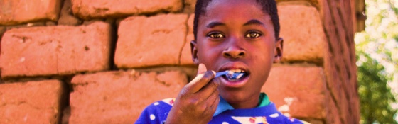 A boy in a Christmas jumper enjoys food from Mary's Meals