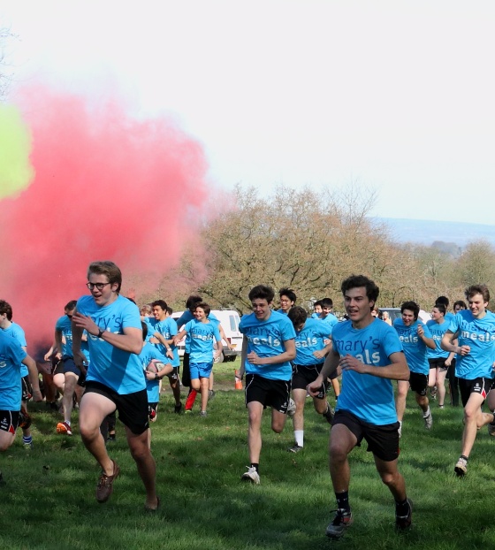 group of fundraisers racing from the start line with coloured smoke plumes overhead