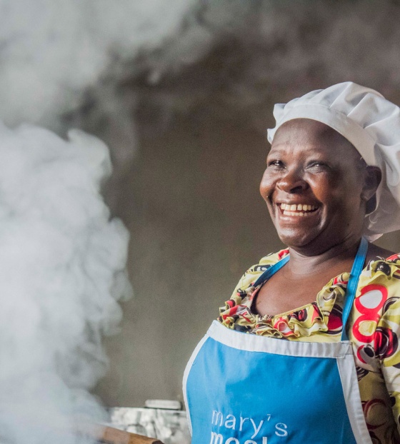A volunteer cook laughs as she prepares food