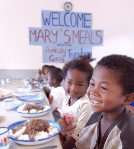 children smiling happily in front of bowls full of food