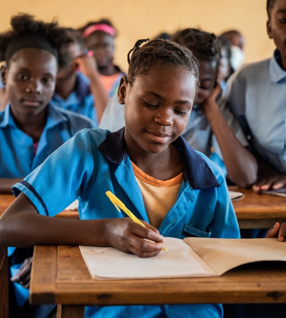A child from Zambia writing in her jotter while learning in class. 