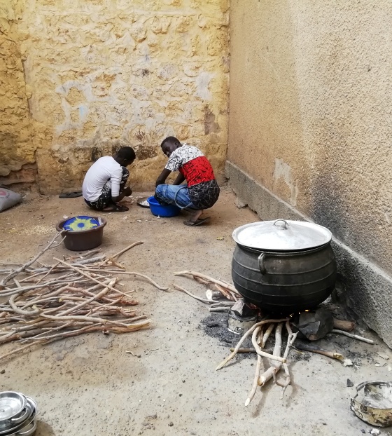 a stove sitting atop a bundle of wood with two people crouched in the corner of the room