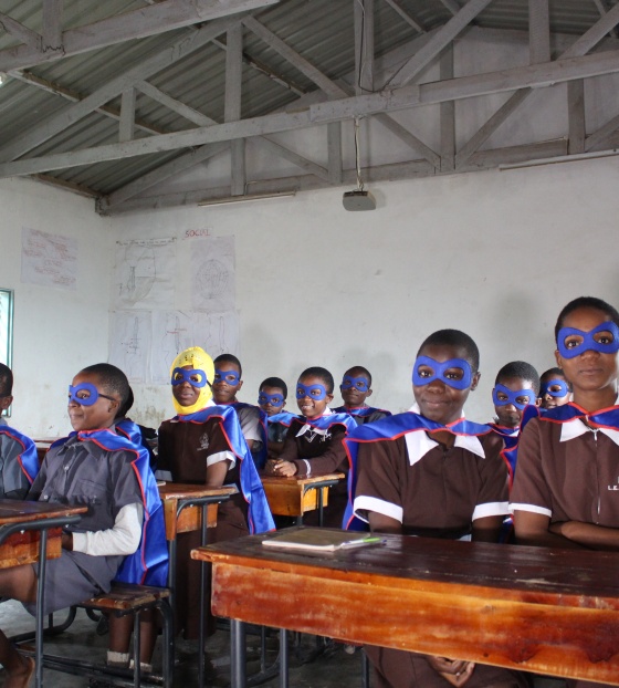 classroom full of children dressed as superheroes with capes and masks