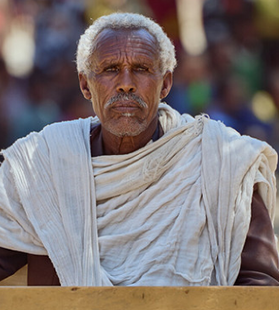 Village elder in Tigray sitting at a desk against the backdrop of a crowd which had gathered.