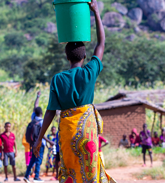 Image of a woman balancing a jug on her head. 