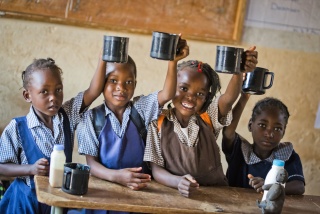 group of young girls holding metallic mugs aloft