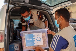 men wearing masks unloading food aid from the back of a van