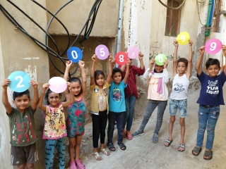 a group of children holding up paper signs that combine to show Mary's Meals latest feeding figure