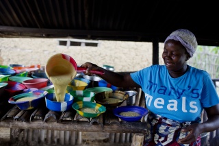 Mary's Meals volunteer pouring porridge into smaller bowls