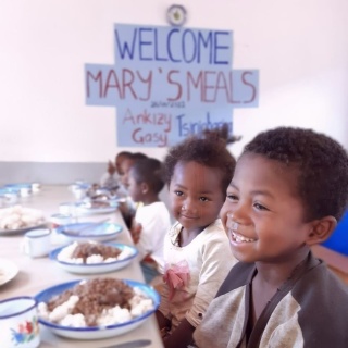 children smiling happily in front of bowls full of food