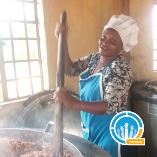 Mary's Meals volunteer stirring a huge cauldron of steaming food