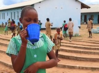 young girl drinking from a blue mug