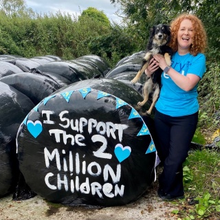 a woman holding a dog in front of a sign that reads 'I support the 2 million children'
