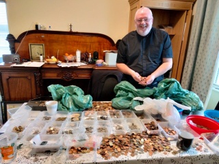 man sitting on the floor counting copper coins