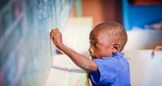 A child writes on a blackboard