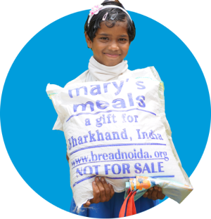 A child in India with a delivery of food from Mary's Meals
