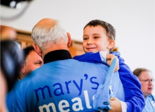 A volunteer carries his grandson at a fundraising event